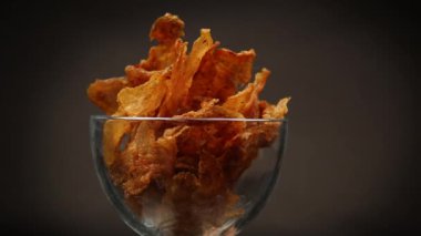 Siyah arka planda izole edilmiş cam bir kasede baharatlı kurutulmuş et. Bira çerezi.