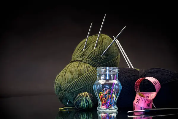 wool yarn, knitting needles and other tools for hand knitting, isolated on a black background.