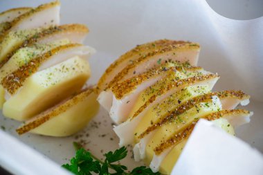 Domuz yağı ve baharatla doldurulmuş çiğ patates, fırın kağıdında pişirmeye hazır..