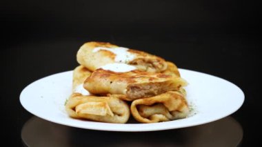 Ekşi krema ve baharatla dolu bir tabakta ince kızarmış krep. Ukrayna yemekleri.