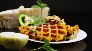 Kara arka planda izole edilmiş bir tabakta lahana ve havuçtan yapılmış iki renkli sebzeli waffle.