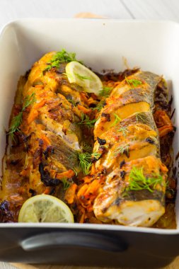 Baharat ve sebzelerle pişirilmiş balık seramik bir kapta..