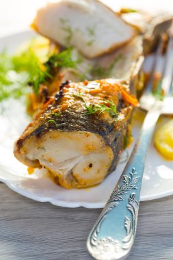 Baharat ve sebzelerle pişirilmiş balık ahşap bir masada bir tabakta..