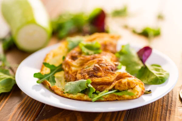 Kızarmış omlet, kabak ve ahşap bir masada otlar..