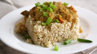 Ahşap bir masada et sosu ve sebzelerle pişirilmiş bulgur..