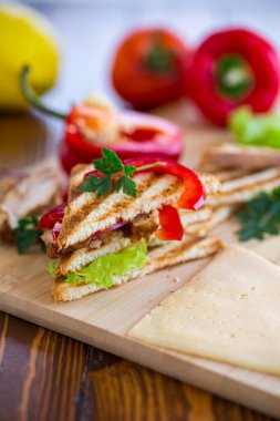 Tavuklu kızarmış ekmek, salata, ahşap bir masada yeşiller. .