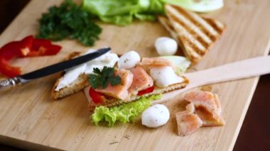 Kızarmış ekmek, somon, krem peynir, salata, ahşap bir masada. .