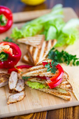 Tavuklu kızarmış ekmek, salata, ahşap bir masada yeşiller. .