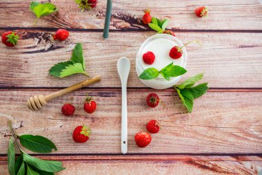 Çilekli kavanozda ev yapımı tatlı yoğurt, ahşap bir masada. .