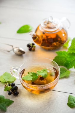 Frenk üzümünden bitki çayı ve bir fincanda böğürtlen ve bir çaydanlıkta, açık ahşap bir masada