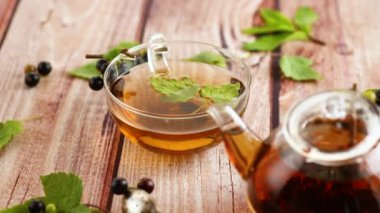 Frenk üzümünden bitki çayı ve bir fincanda böğürtlen ve bir çaydanlıkta, ahşap bir masada