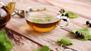 Frenk üzümünden bitki çayı ve bir fincanda böğürtlen ve bir çaydanlıkta, ahşap bir masada