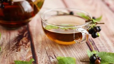 Frenk üzümünden bitki çayı ve bir fincanda böğürtlen ve bir çaydanlıkta, ahşap bir masada