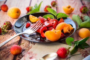 Taze meyve salatası taze çilek ve kayısı, açık ahşap bir masa üzerinde. .