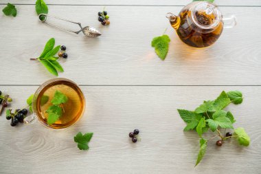Frenk üzümünden bitki çayı ve bir fincanda böğürtlen ve bir çaydanlıkta, açık ahşap bir masada