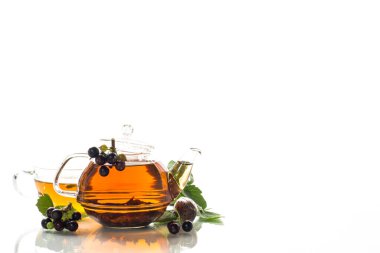 Frenk üzümü yaprağından bitki çayı ve bir fincanda böğürtlen ve beyaz arka planda izole edilmiş bir çaydanlıkta.