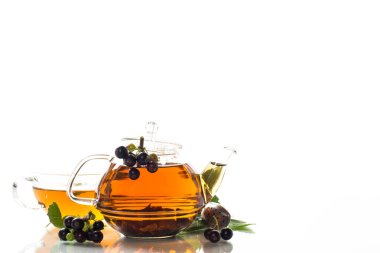 Frenk üzümü yaprağından bitki çayı ve bir fincanda böğürtlen ve beyaz arka planda izole edilmiş bir çaydanlıkta.