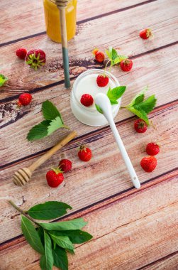 Çilekli kavanozda ev yapımı tatlı yoğurt, ahşap bir masada. .
