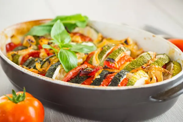 prepared baked zucchini and tomatoes in circles in a ceramic form, vegetable snack .