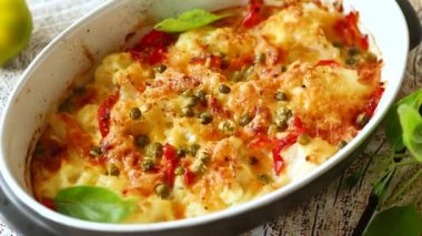 Peynirin altında tatlı biber ve sebzeyle pişirilmiş karnabahar, seramik bir kabın içinde.