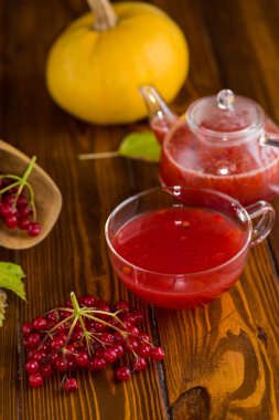 Tahta bir masada olgun kırmızı viburnum 'dan çay .