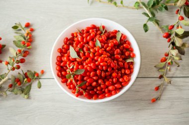 Tahta masadaki bir kasede taze kırmızı goji üzümleri. .