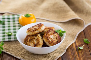 Tahta bir masada, bir kasede kızarmış tavuk pirzolası. .