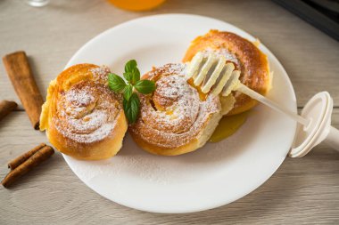Hamur işleri. Süzme peynirli tatlı çörekler ve ahşap bir masada bir tabakta bal .