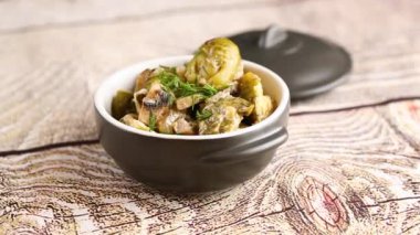 Ekşi krema soslu, mantarlı ve baharatlı Brüksel lahanası, ahşap bir masada seramik bir kasede..