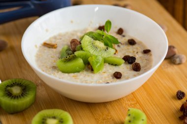 Yulaf ezmesi, kivi, bal ve fındık, ahşap bir masada..