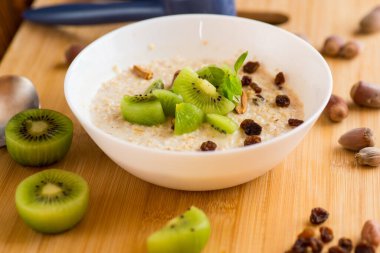 Yulaf ezmesi, kivi, bal ve fındık, ahşap bir masada..
