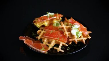 Sebze patatesli waffle ve hafif tuzlu kırmızı balık tabakta, siyah arka planda izole edilmiş..