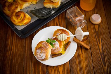 Hamur işleri. Süzme peynirli tatlı çörekler ve ahşap bir masada bir tabakta bal .