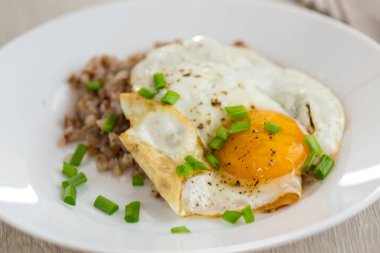 Haşlanmış karabuğdaylı yumurta ve ahşap masada soğan..