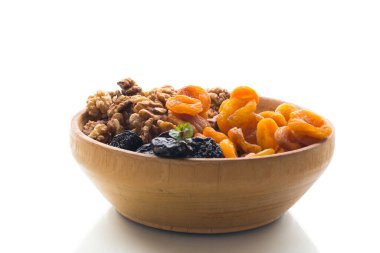 Kuru erik, kayısı ve fındık, beyaz arka planda tahta bir kasede..