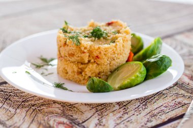 Ev yapımı bulgur, ahşap bir masanın üzerinde, bir tabakta Brüksel lahanası. .