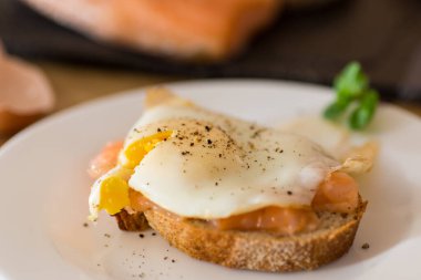 Hafif tuzlu kırmızı balıklı bir dilim ekmek ve kahvaltıda pişmiş yumurta..