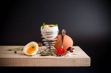 Kırmızı havyar kaşıkta ve sabah kahvaltıda haşlanmış yumurta, siyah arka planda izole edilmiş..