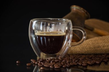 Siyah arka planda kahve çekirdekli bir fincan sıcak kahve..