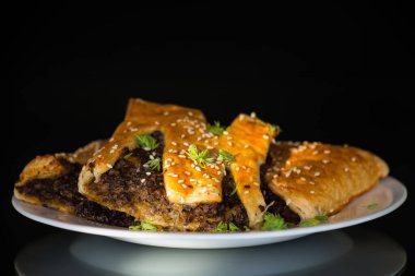 Mantar dolgulu çıtır puf börekler ve siyah arka planda izole edilmiş susam tohumları..