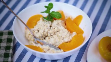 Beyaz kâse içinde şeftali kokulu yulaf ezmesi..