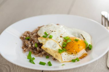 Yağda yumurta ve haşlanmış karabuğdaylı sıcak kahvaltı servisi..