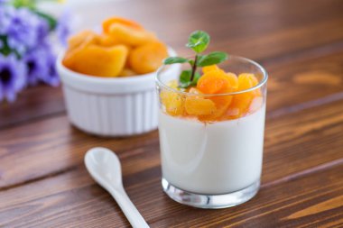 Açık meyveli yoğurt ve koyu ahşap masada kurutulmuş kayısı..