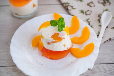 Konserve şeftali parçaları ahşap masada çok katmanlı jöle içinde.