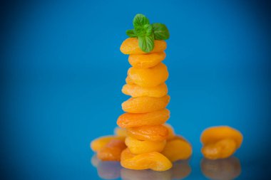 Mavi arka planda kurutulmuş kayısı ve taze naneli estetik bileşim..