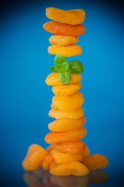 Parlak mavi arka planda yeşil naneli izole edilmiş kurumuş kayısılar..