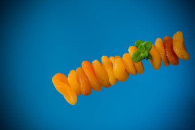 Parlak mavi arka planda yeşil naneli izole edilmiş kurumuş kayısılar..