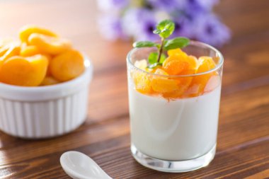 Açık meyveli yoğurt ve koyu ahşap masada kurutulmuş kayısı..