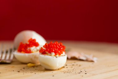 Kırmızı arka planda kırmızı havyarlı haşlanmış yumurta..