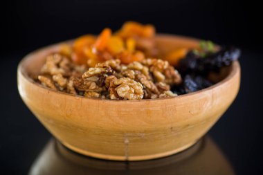 Kuru erik, kurumuş kayısı ve fındık, arka planda bir ahşap kasede..